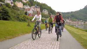 Hier werden Ihnen radfahrende Damen und Herren in idyllischer Landschaft gezeigt